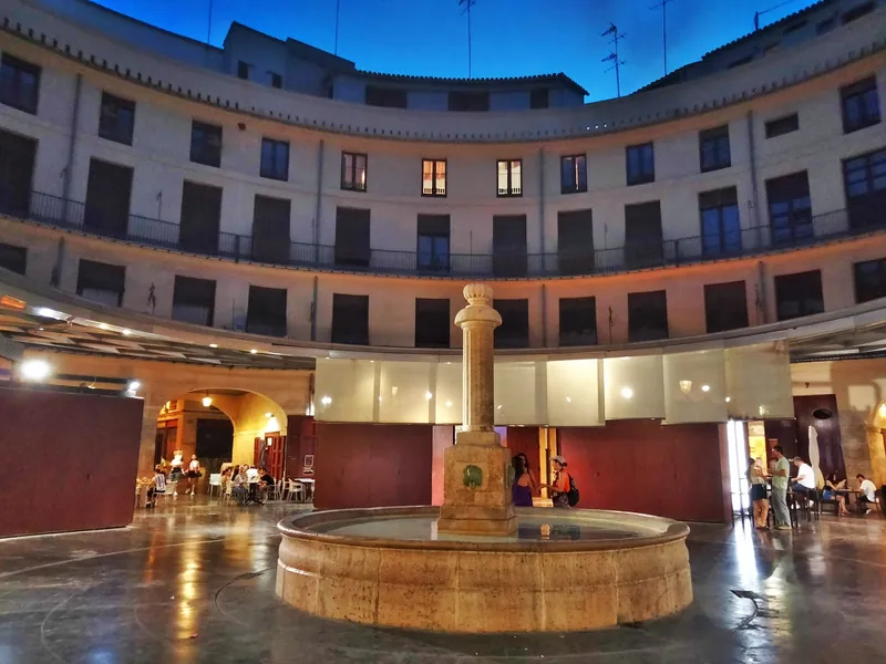 Runder Innenhofplatz Plaça Redona in der Altstadt von Valencia mit Brunnen und Terrassen in der Abenddämmerung