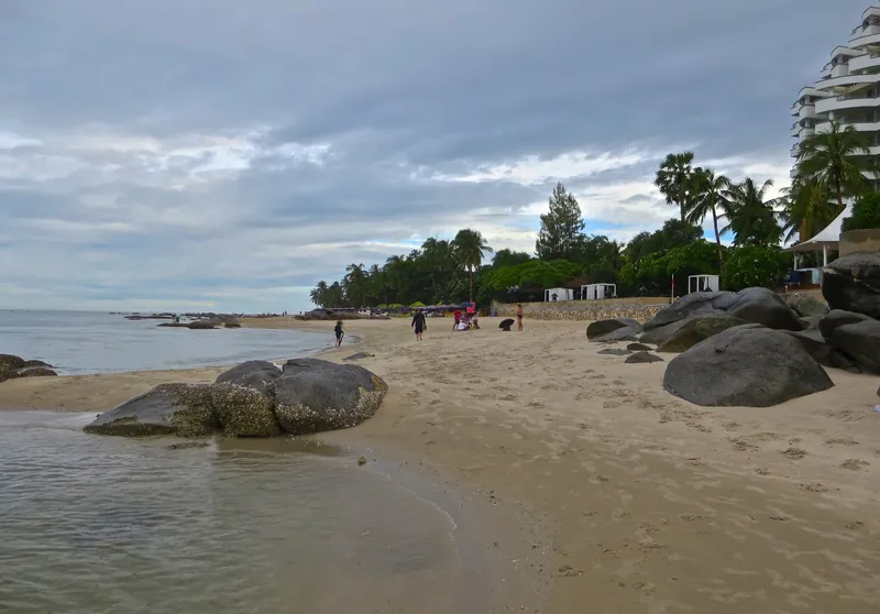 Öffentlicher Strand von Hua Hin mit Granitfelsen und Hotelhochhaus