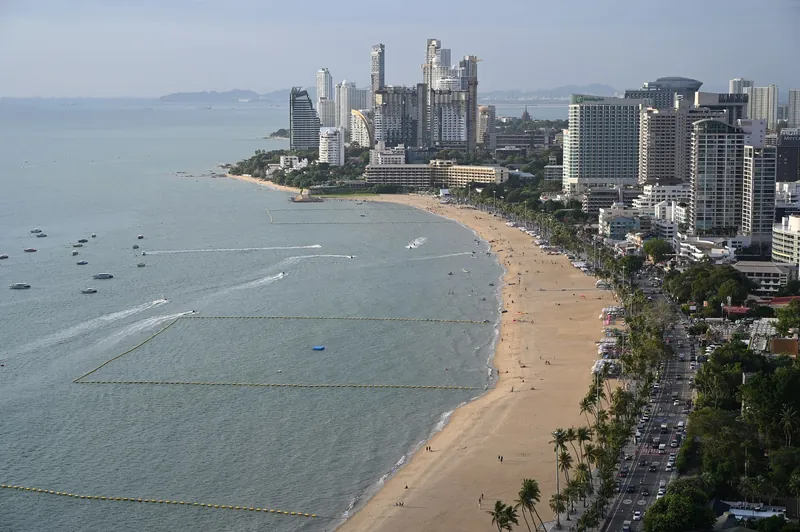Luftaufnahme von Pattaya Beach: Hochhaushotels und Baukräne reichen bis an die Strandstraße (dichte Küstenbebauung)