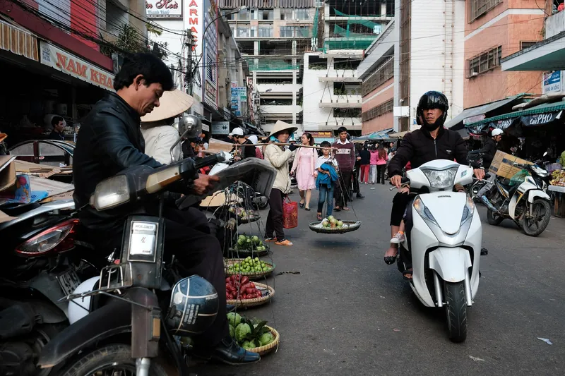 Vegetable sellers with baskets and scooters on the market street in Da Lat
