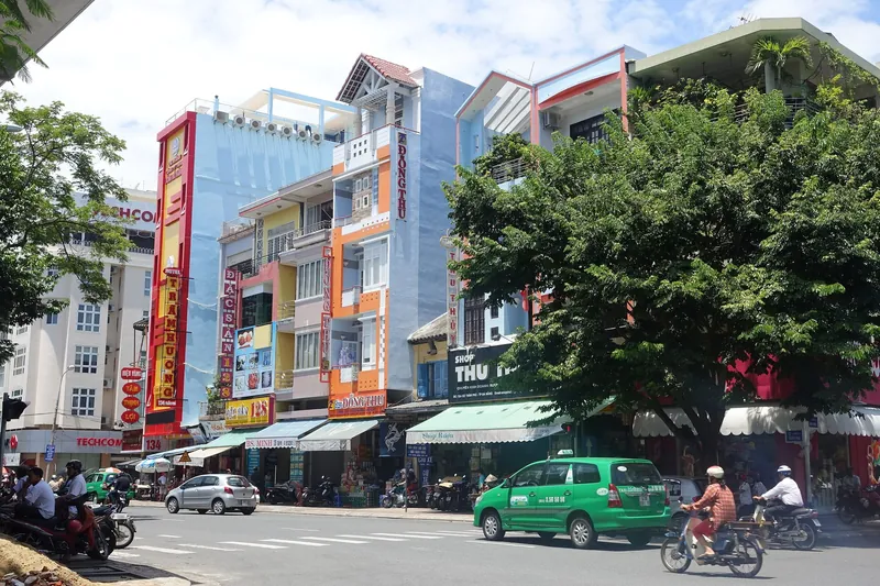 Street of colourful terraced houses with a taxi and scooters in central Da Nang