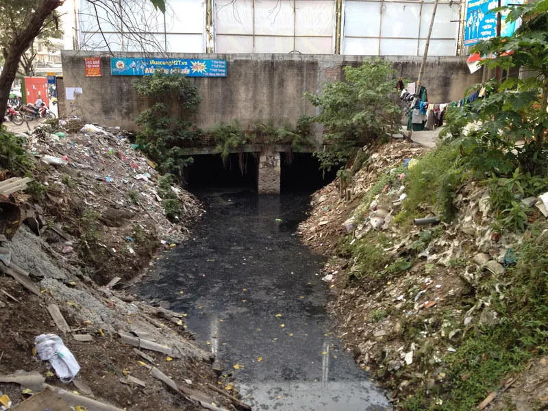 Entwässerungskanal an der Thai-Ha-Straße in Hanoi mit vermüllten Uferböschungen und schwarzem Abwasser