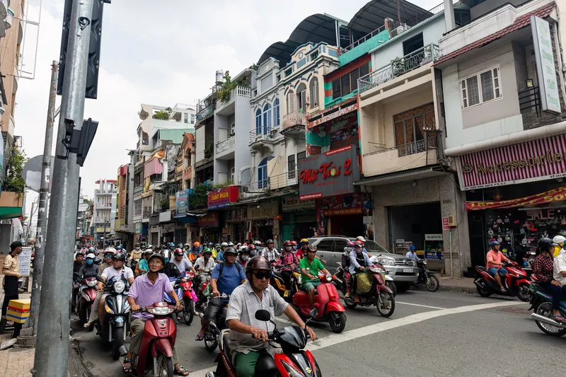Scooters at a junction in front of terraced houses and shops in Ho Chi Minh City
