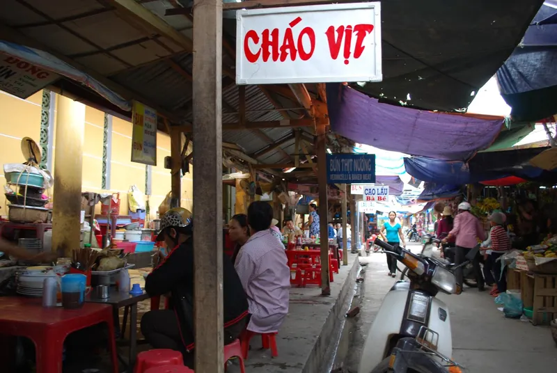 Garküchengasse im Markt von Hoi An mit Schildern für Chao Vit, Bun thit nuong und Cao Lau