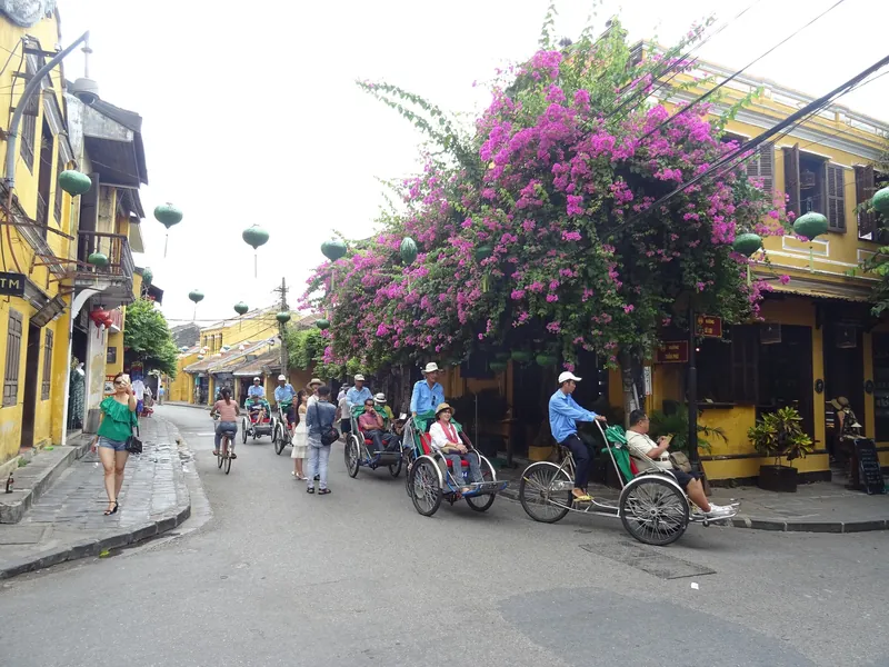 Fahrradrikschas (Cyclos) mit Fahrgästen in einer Altstadtstraße von Hoi An