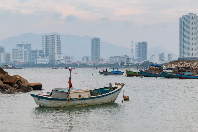 Fischerboote an der Anlegestelle bei der Insel Hon Do vor der Hochhauskulisse von Nha Trang